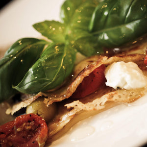 Vegetarian savoury crepe filled with feta cheese, olives and sun-dried tomatoes with a bay leaf garnish and drizzled with olive oil