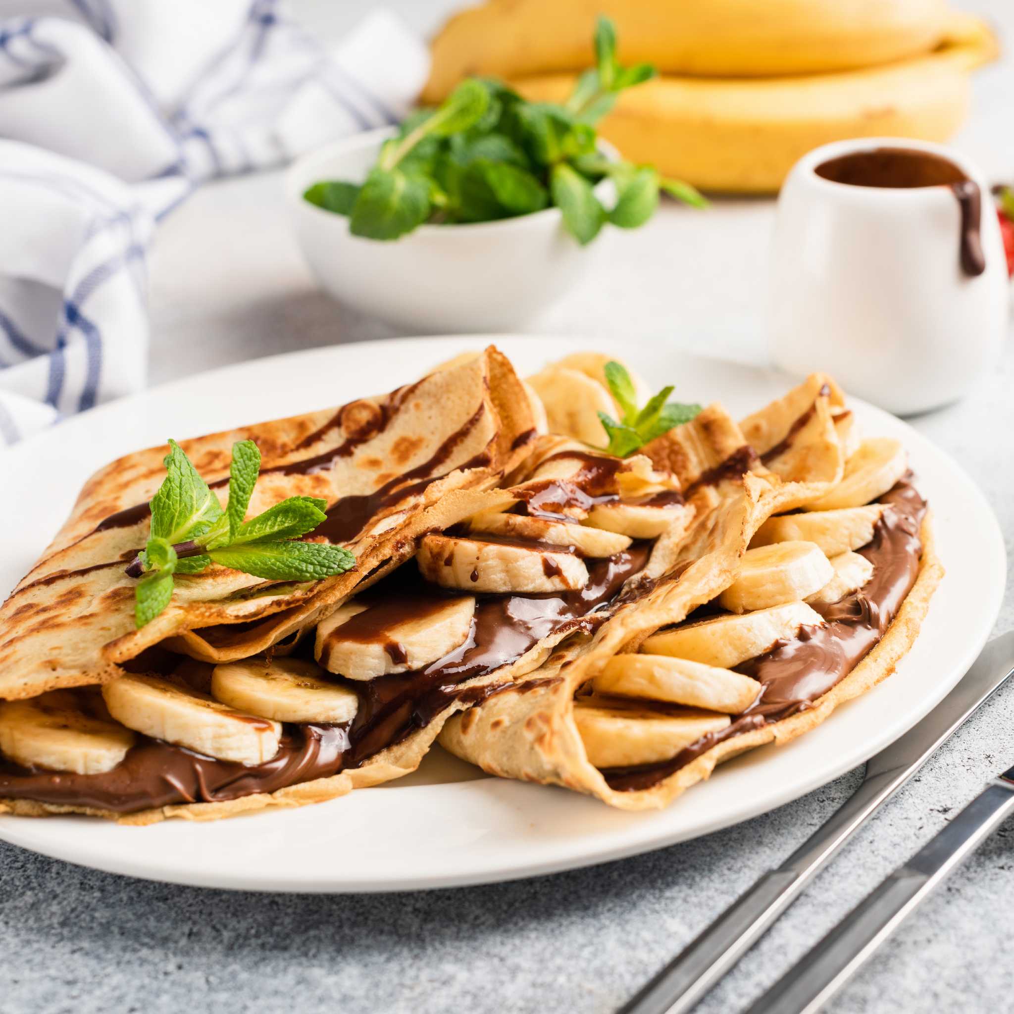 Crepes filled with Nutella and sliced banana and garnished with sprigs of mint