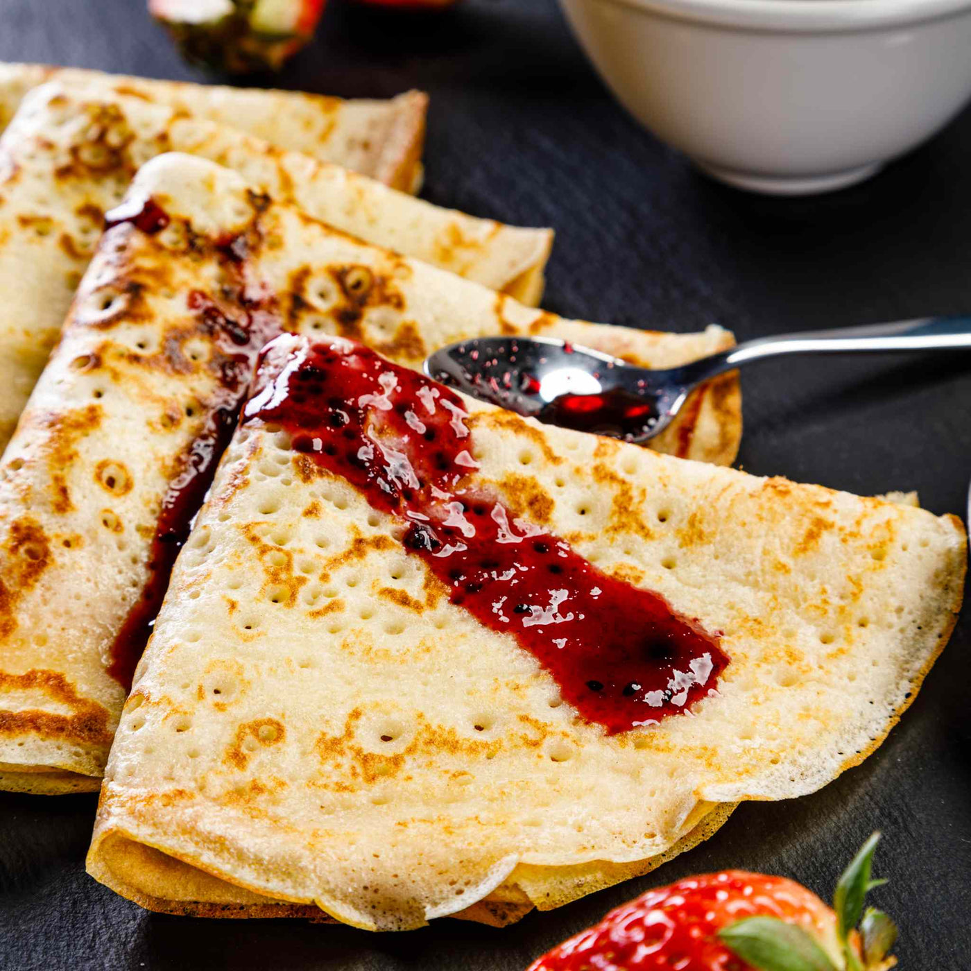 Stack of pancakes covered in strawberry jam